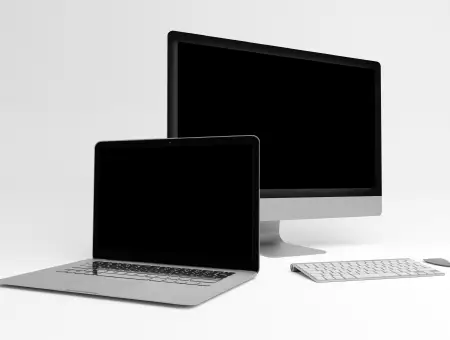 A laptop and desktop with blank screens against a white background.